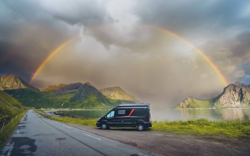 Camper junto a la orilla de un lago y frente al arco iris.